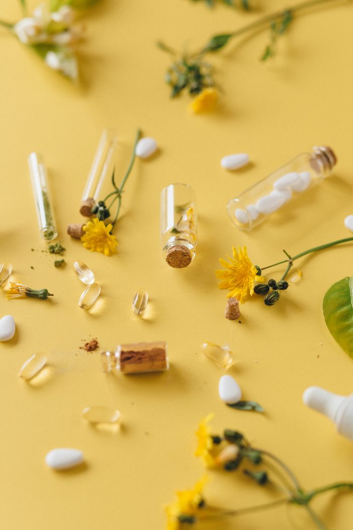 Aesthetic display of medicinal herbs and pharmaceutical capsules on a yellow background.